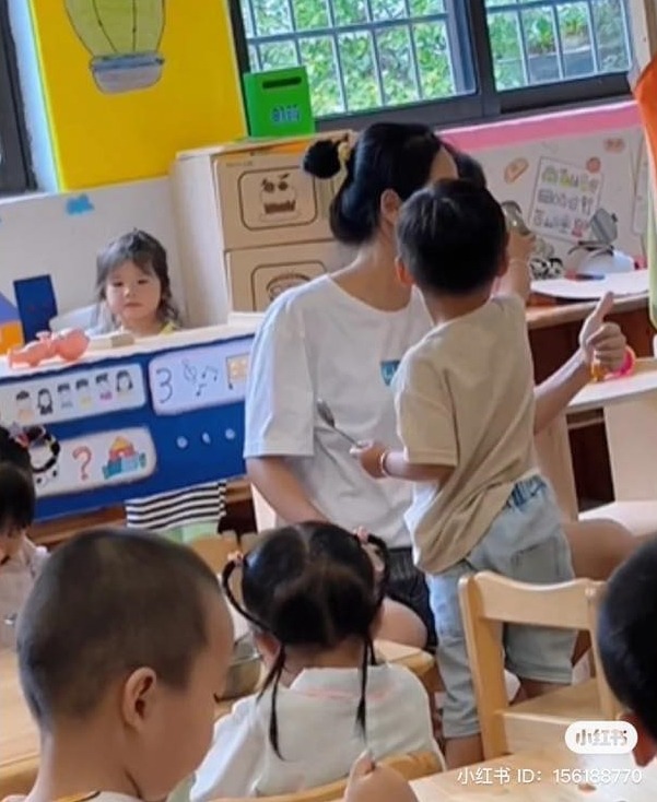 Cậu bé giơ chiếc bát không trước mặt cô giáo