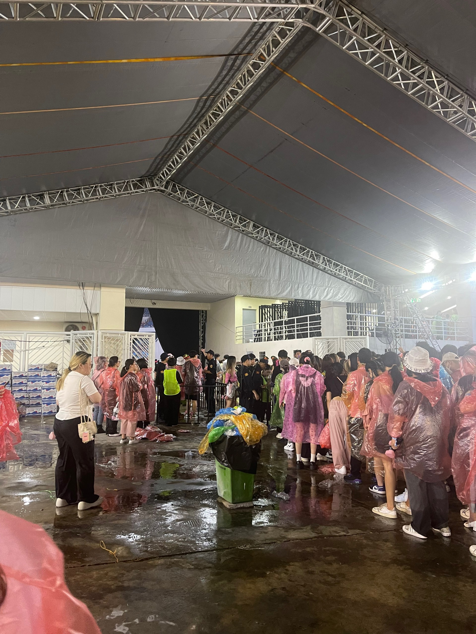 Mọi người mang áo mưa xếp hàng vào cổng sân vận động