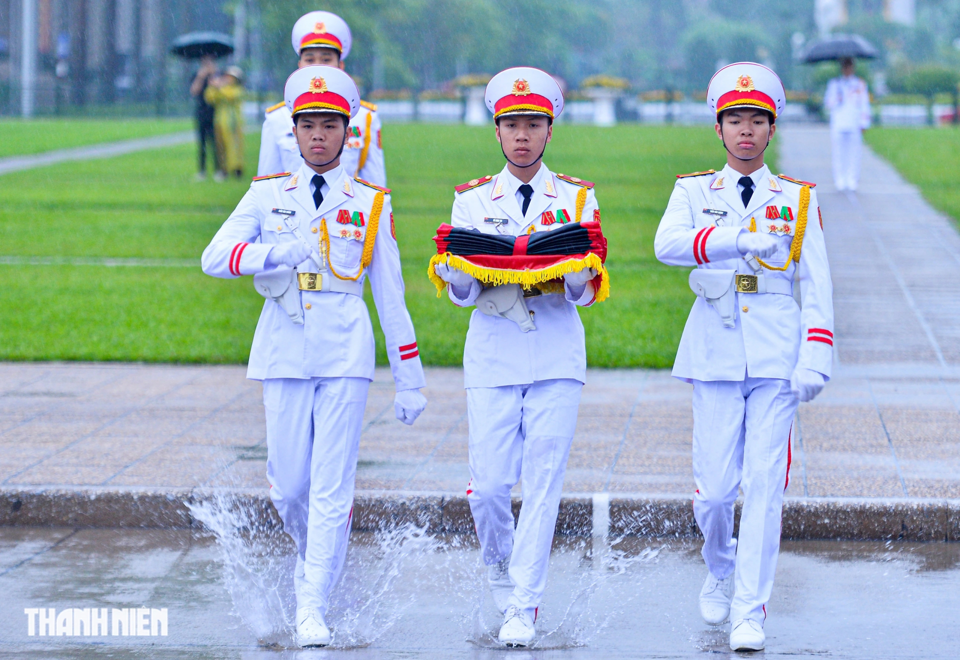 Ba chiến sĩ mang khay đựng Quốc kỳ và dải băng đen bước lên bục, chuẩn bị cho lễ thượng cờ rủ ẢNH: ĐÌNH HUY