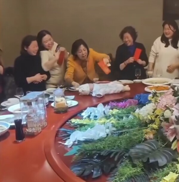 Cả nhà đặt bé sơ sinh lên bàn ăn rồi xoay tròn để lì xì, hành động sau đó gây bức xúc