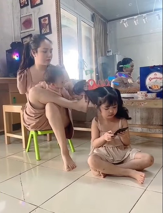 Clip người mẹ trẻ khuyết một tay cột tóc bằng chân cho con gây chú ý