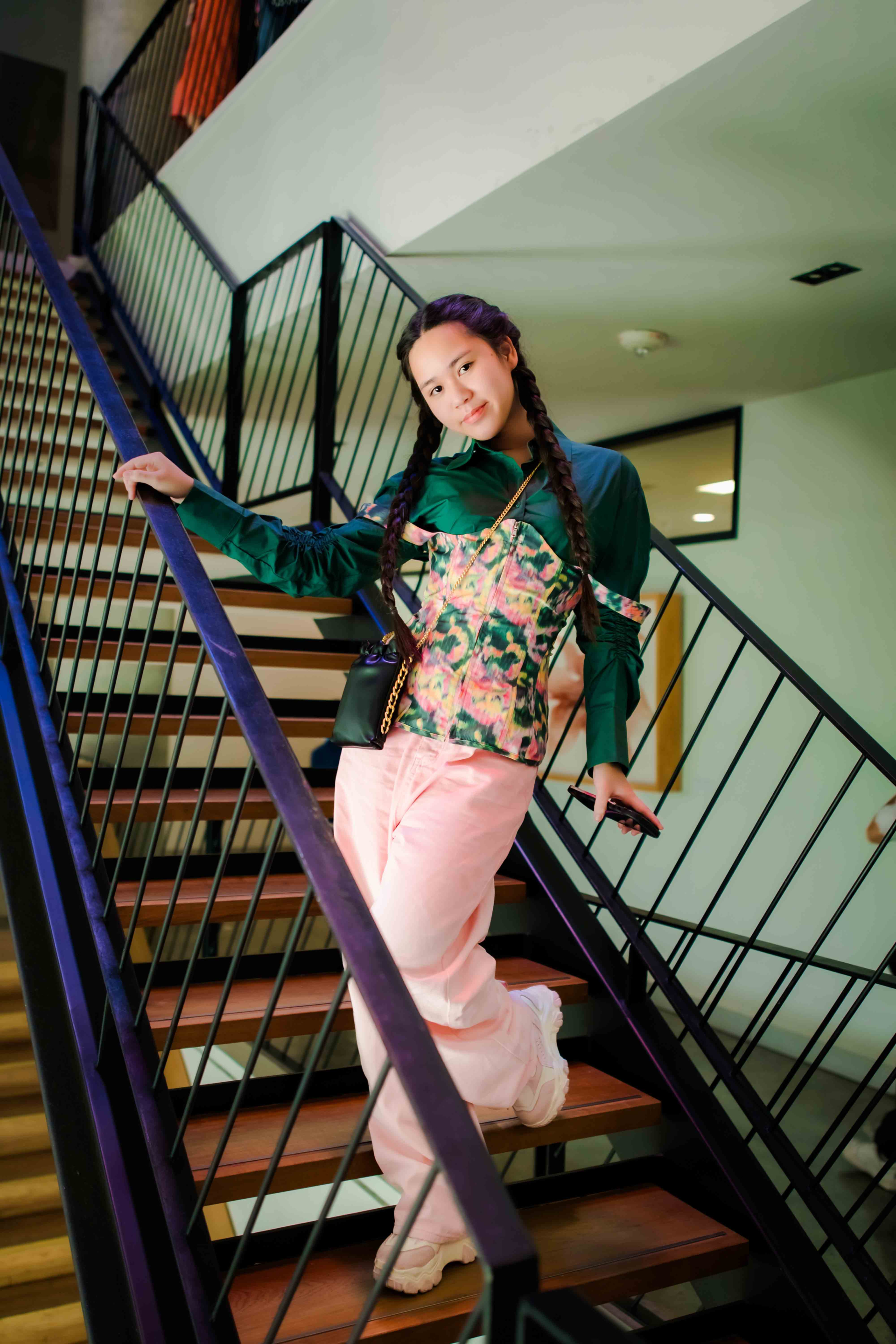 Bella Vũ tạo dáng ở phòng chờ sân bay với bộ váy xếp, áo khoác màu hồng ngọt ngào.