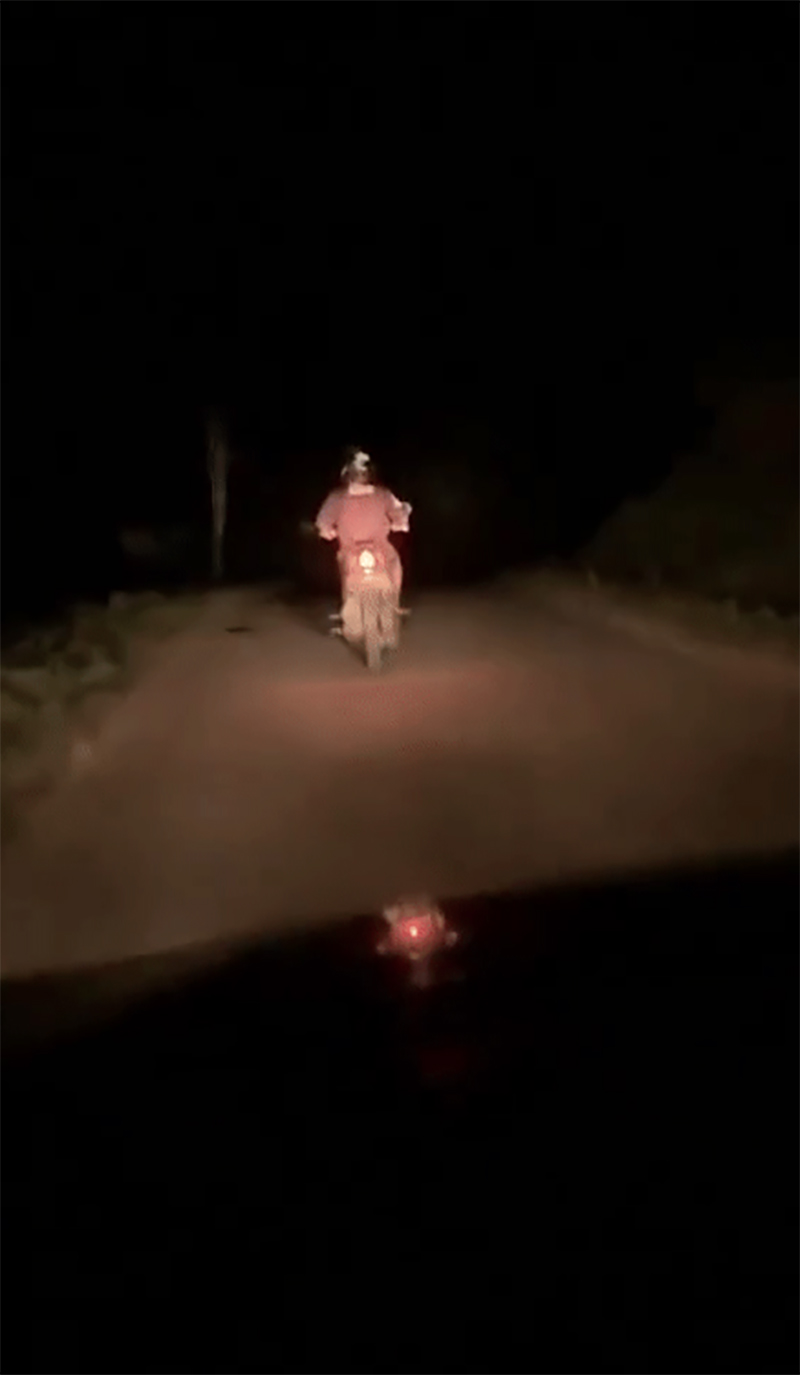 Tài xế xe ô tô rọi đèn cho người chạy xe máy phía trước trên con đường tối om