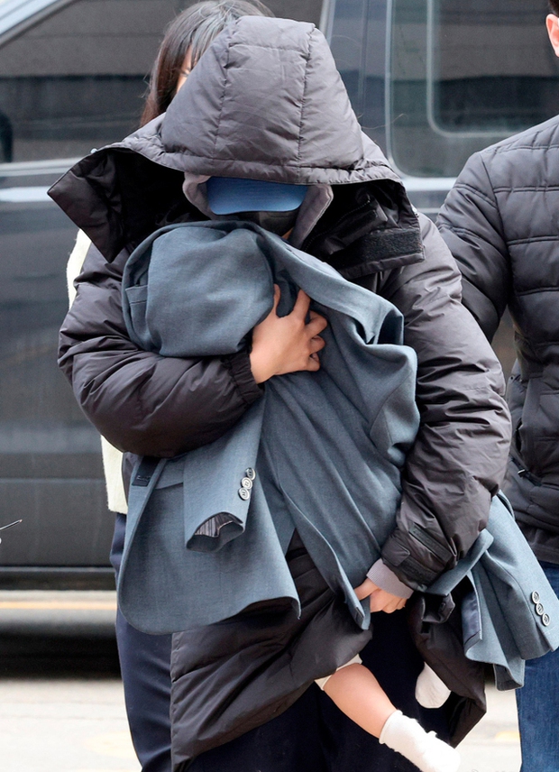 Người phụ nữ ôm một đứa trẻ đến trình diện đồn cảnh sát