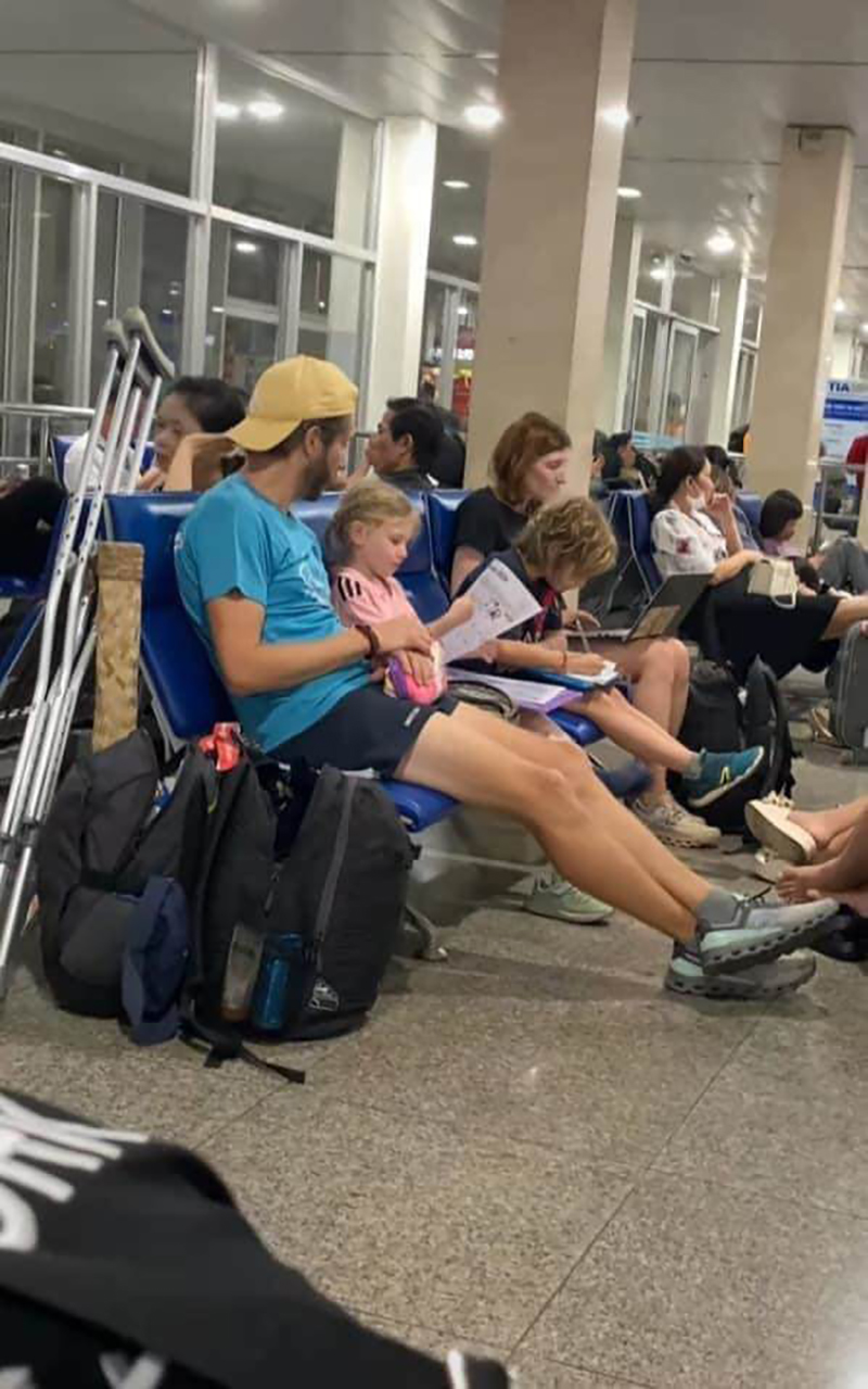 Cặp trẻ em của gia đình người nước ngoài tập trung đọc sách trong lúc chờ ở sân bay