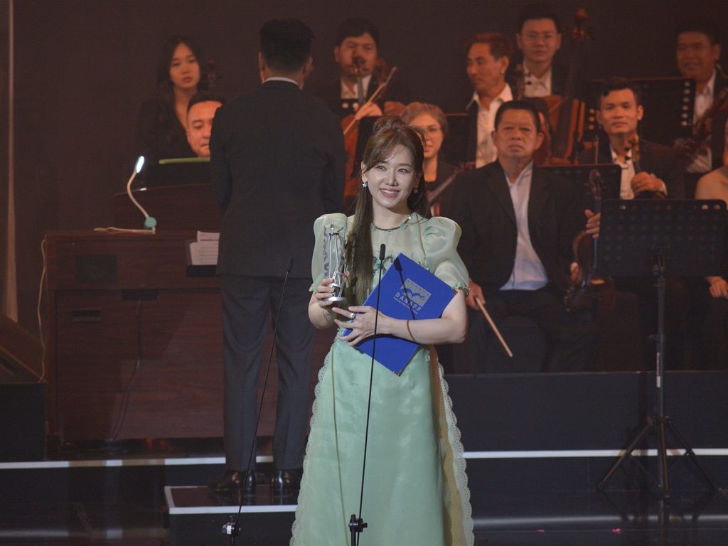 Hari Won thay mặt Trấn Thành nhận giải 'Đạo diễn xuất sắc nhất' tại lễ trao giải Liên hoan phim châu Á - Đà Nẵng.