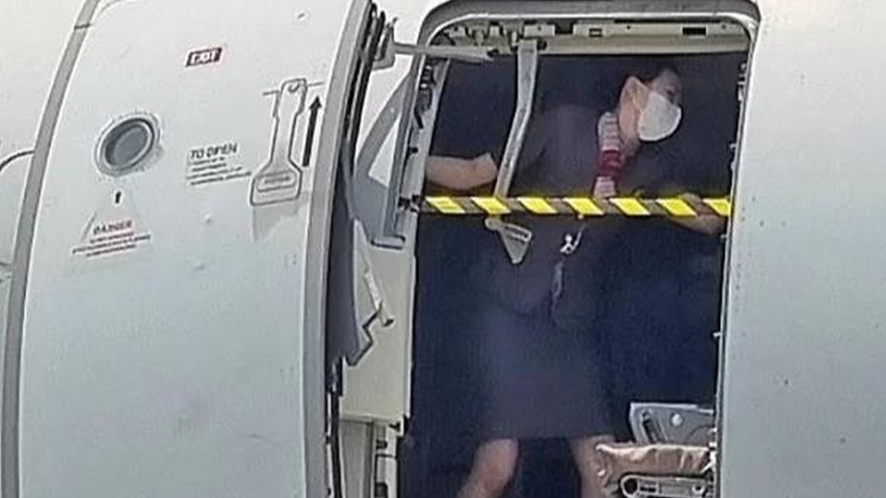 Hình ảnh nữ tiếp viên hàng không nỗ lực đứng chặn cửa trên máy bay ở độ cao 200m.