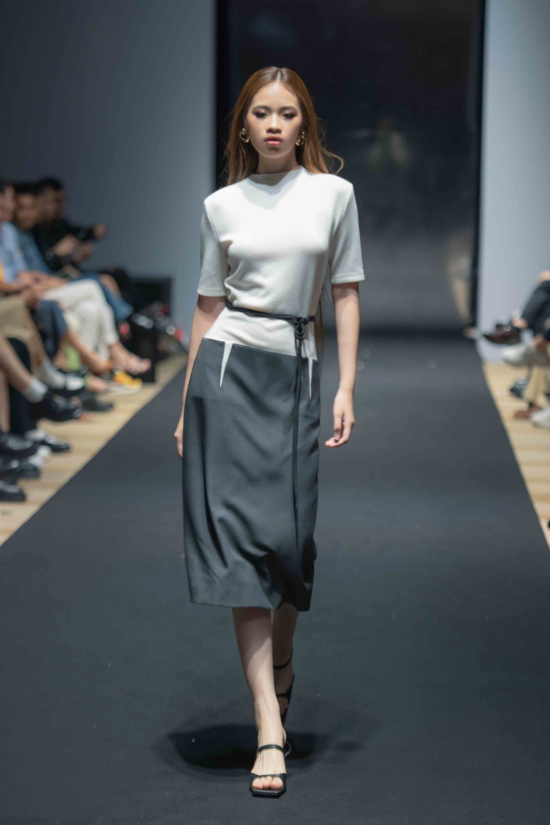 Trình diễn cho thiết kế của thương hiệu Decos, Bảo Hà diện set váy áo nhã nhặn mang hai tone màu trắng và đen lấy thắt lưng mảnh làm điểm nhấn.