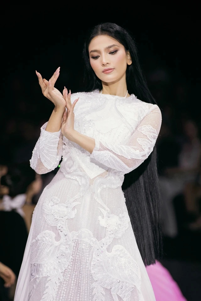 Á hậu Trương Thị May trình diễn áo dài ren đính kết tỉ mỉ họa tiết mây và chim phượng, kết hợp váy dập ly thướt tha và áo yếm ở vị trí vedette