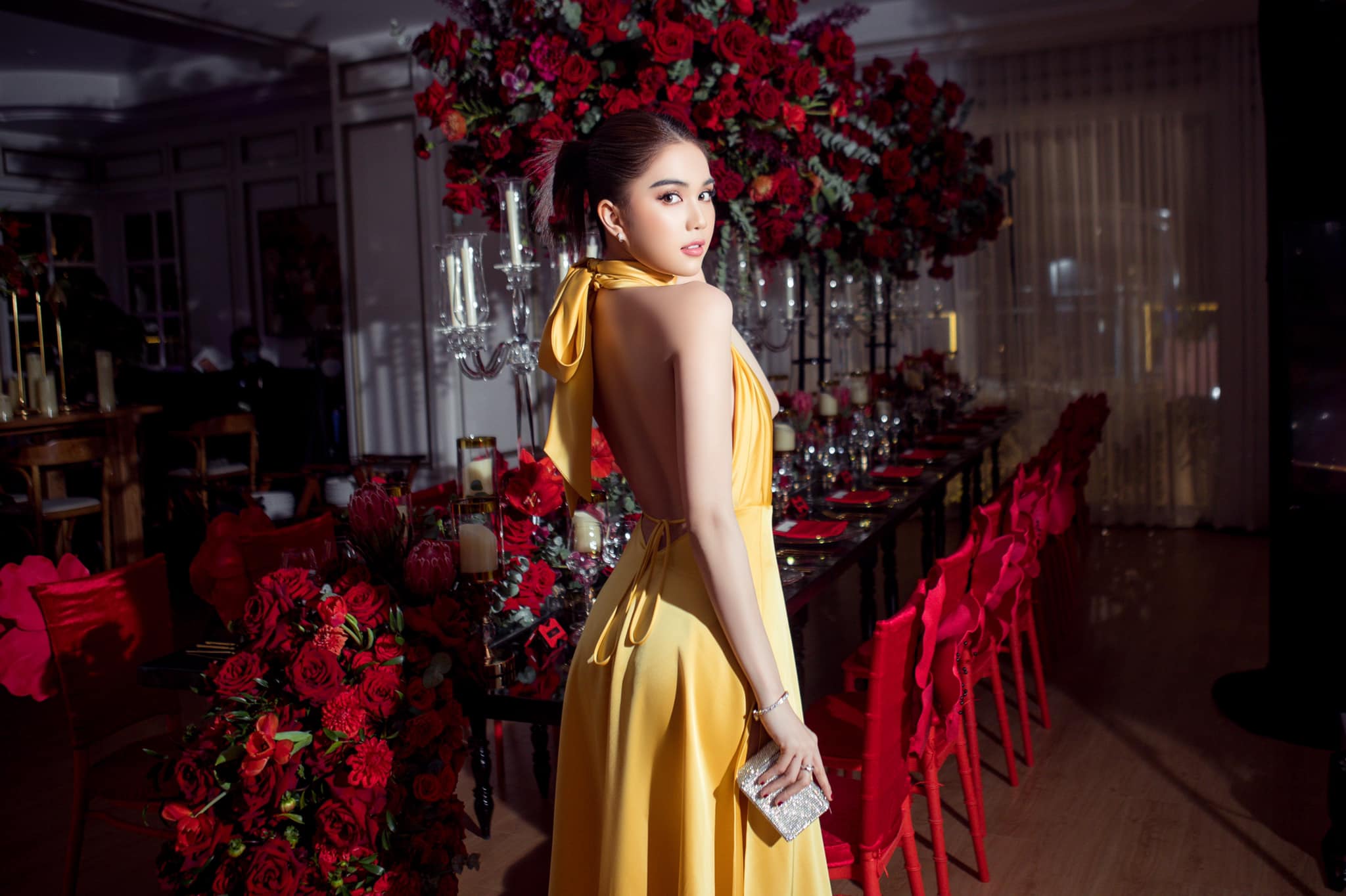 Trong bữa tiệc cuối năm tại biệt thự của Vũ Khắc Tiệp, Ngọc Trinh xuất hiện nổi bật với chiếc váy màu vàng rực rỡ. Thiết kế này được tạo nên bởi NTK Đỗ Long với chất liệu lụa, kiểu dáng mang đến cảm hứng như áo yếm của người phụ nữ Việt.