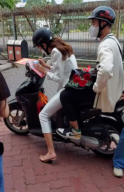 Thuỳ Tiên cặm cụi kí tặng fan khi ngồi trên xe máy