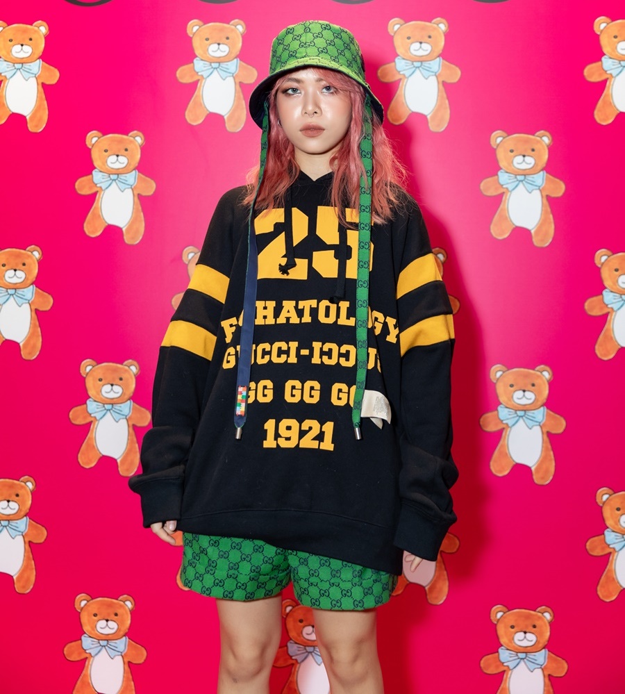 Nữ rapper Tlinh diện áo oversize đậm chất hip hop, kết hợp cùng nón và quần short xanh lá mang hoạ tiết Gucci
