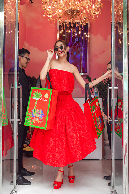 Võ Hoàng Yến chọn gam màu đỏ váy tùng xòe điệu đà tiểu thư , cô yêu thích các chiếc túi shopping bag của hai nhà thiết kế với hoạ tiết mùa xuân 2021