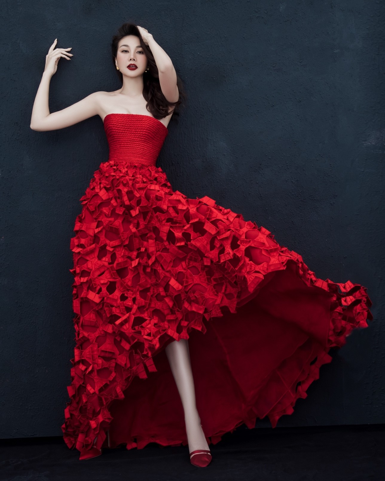 Vẻ đẹp nồng nàn đầy tính nữ được thể hiện qua mẫu đầm màu đỏ với phần thân trên được dựng phom corset,  phần tùng váy được kết từ những lớp nơ double satin. 