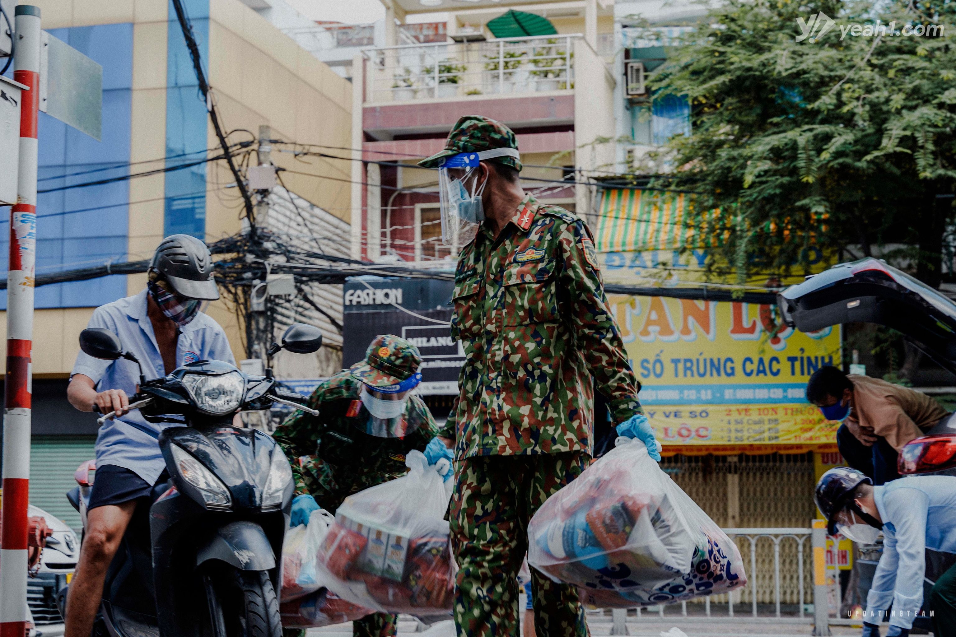 Các chiến sĩ bộ đội đang phát túi an sinh cho người dân Sài Gòn. Nhìn khối lượng hàng hóa cũng thấy được sự cồng kềnh và sức nặng, nhưng điều này vẫn không ngăn cản được bước chân và sự nhanh nhẹn của họ.