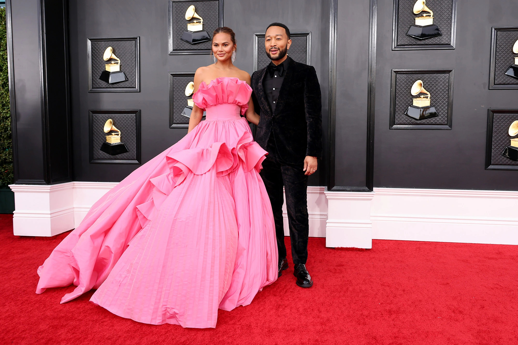 Một cặp đôi khác cũng chiếm spotlight trên thảm đỏ Grammy 2022 là vợ chồng Chrissy Teigen và John Legend. Chủ nhân hit 'All of me' lịch lãm trong suit đen còn bà xã Chrissy đã 'quét sạch' thảm đỏ bằng mẫu váy hồng nổi bật, thiết kế bồng bềnh nữ tính.