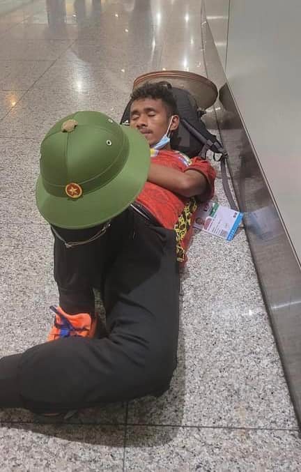 Hình ảnh nam VĐV ngủ tạm ở sân bay trong lúc chờ đến giờ khởi hành vẫn không quên đặt chiếc mũ cối của Việt Nam trên người vô cùng trân trọng